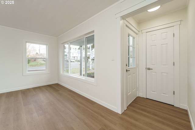 entryway with ornamental molding and hardwood / wood-style floors