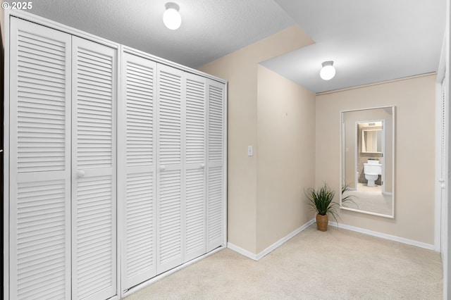 corridor featuring carpet floors, baseboards, and a textured ceiling