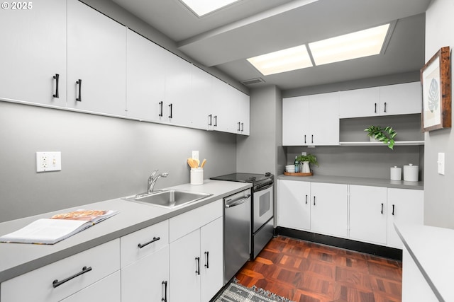 kitchen featuring sink, dark parquet flooring, white cabinets, and appliances with stainless steel finishes