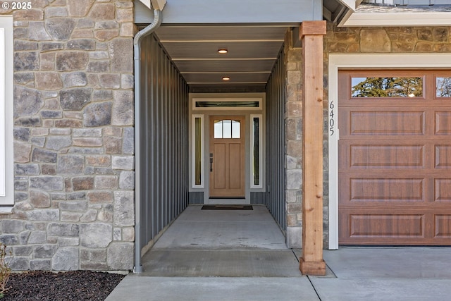 doorway to property with stone siding and a garage