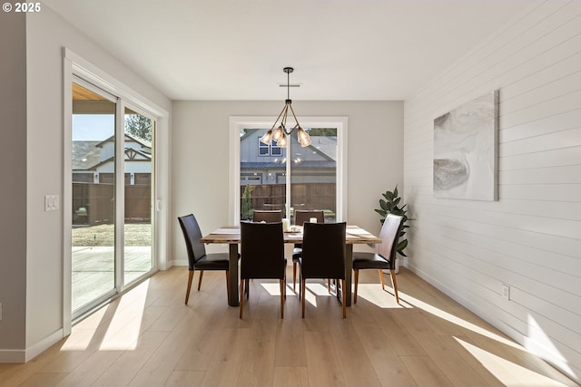 dining space featuring a chandelier, baseboards, and light wood-style flooring