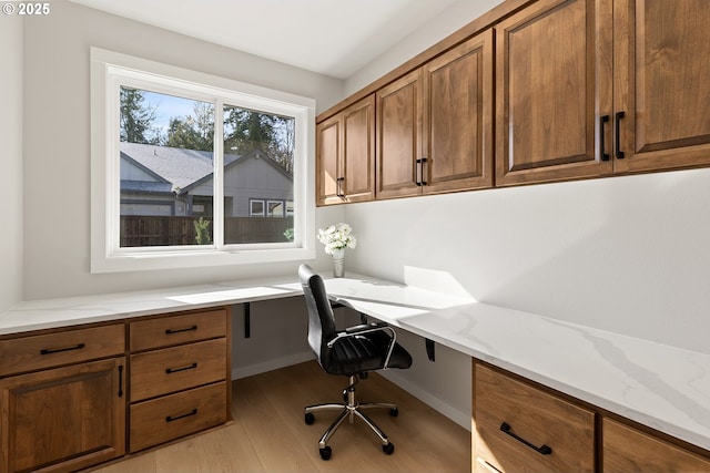 office area with light wood finished floors and built in study area