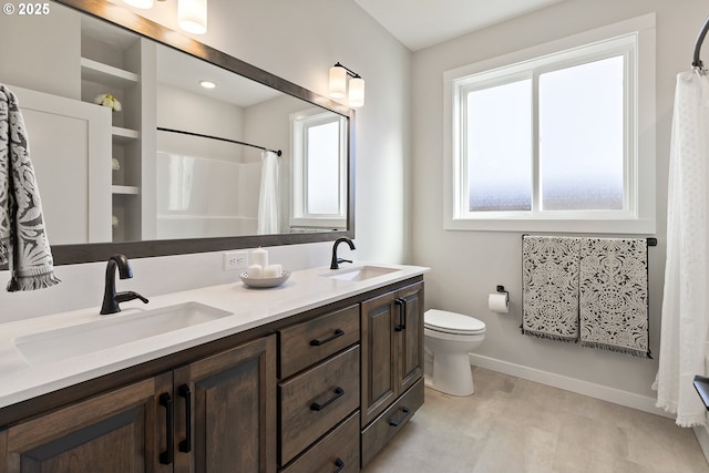 bathroom with a sink, baseboards, toilet, and double vanity