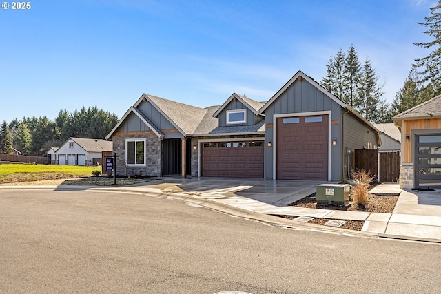 view of front of property featuring stone siding, board and batten siding, driveway, and fence