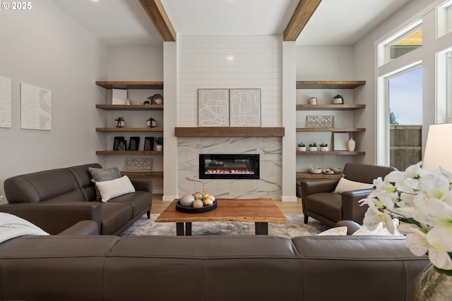 living area with beam ceiling, a fireplace, built in shelves, and wood finished floors