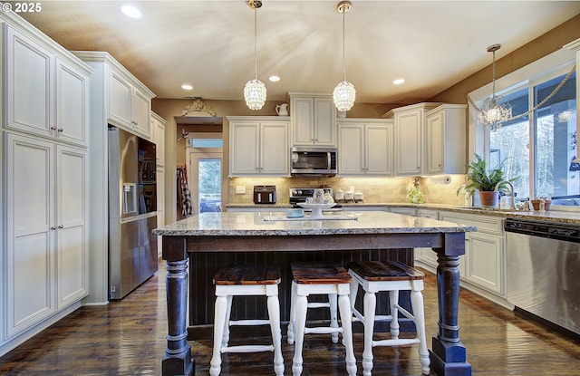 kitchen featuring pendant lighting, a wealth of natural light, stainless steel appliances, and a center island