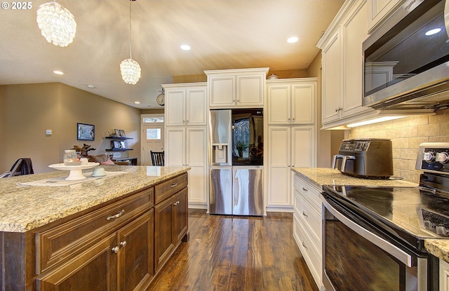 kitchen with appliances with stainless steel finishes, decorative light fixtures, tasteful backsplash, light stone countertops, and dark wood-type flooring