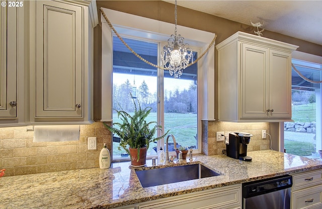 kitchen with sink, tasteful backsplash, light stone counters, stainless steel dishwasher, and pendant lighting