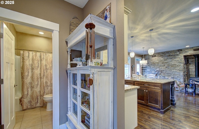 interior space featuring vanity, hardwood / wood-style floors, toilet, and shower / bathtub combination with curtain