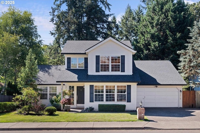 traditional-style home featuring fence, a shingled roof, a front lawn, a garage, and aphalt driveway