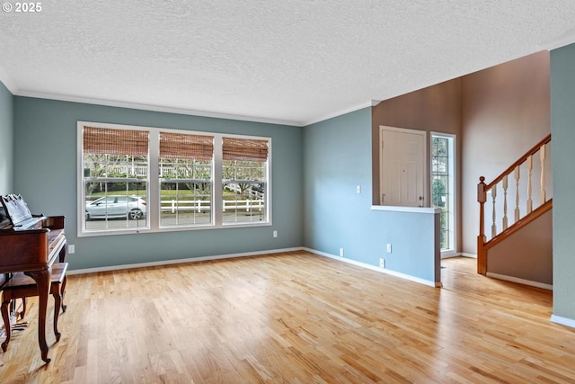 living area featuring stairs, wood finished floors, baseboards, and a textured ceiling