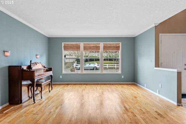 interior space with baseboards, a textured ceiling, wood finished floors, and ornamental molding