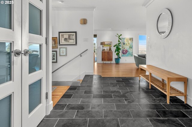 entryway with ornamental molding and french doors