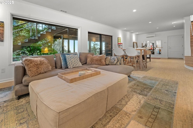 living room with crown molding, light hardwood / wood-style flooring, and a wall unit AC