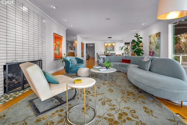 living room featuring wood-type flooring, a fireplace, and crown molding