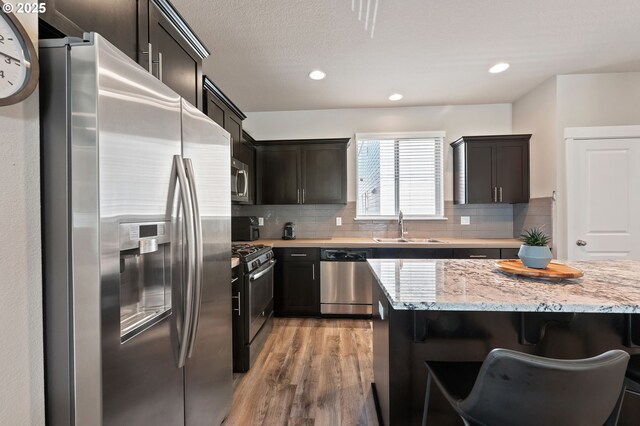 14139 SW Burlwood Ln, Beaverton, OR 97005 - kitchen with appliances with stainless steel finishes, light wood-type flooring, light stone counters, backsplash, and recessed lighting