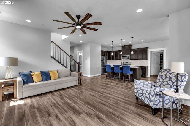 living area with dark wood finished floors, ceiling fan, recessed lighting, stairway, and baseboards