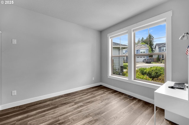 unfurnished dining area featuring dark wood-type flooring and baseboards