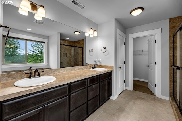 bathroom with a shower stall, a spacious closet, double vanity, baseboards, and tile patterned floors
