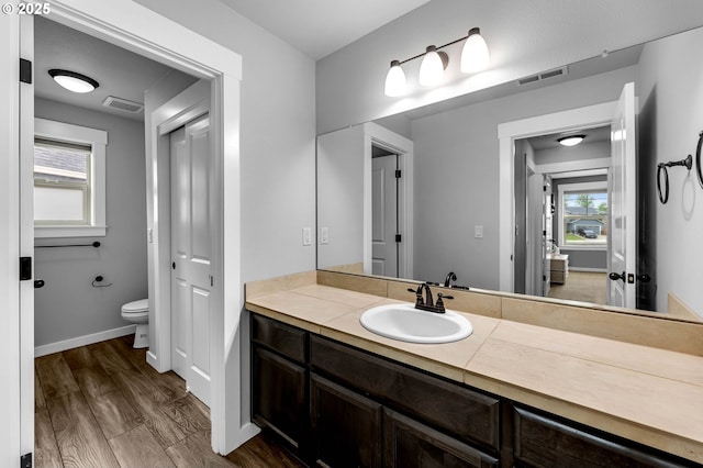 bathroom featuring toilet, wood finished floors, vanity, and baseboards