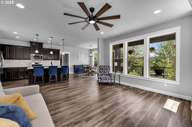 living area featuring ceiling fan, recessed lighting, dark wood finished floors, and baseboards