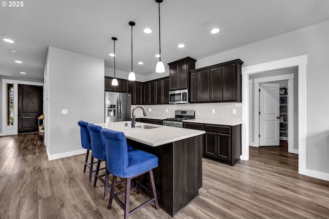 kitchen with stainless steel appliances, a sink, light wood-style flooring, light countertops, and recessed lighting