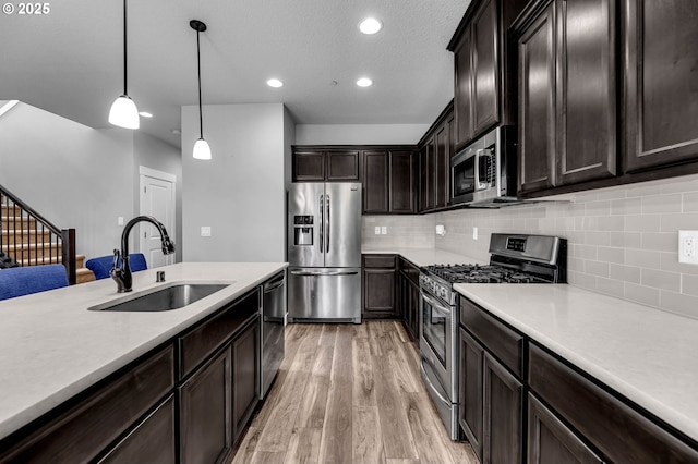 kitchen with stainless steel appliances, a sink, light wood-style floors, light countertops, and recessed lighting