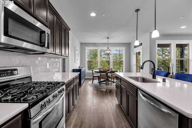 kitchen featuring appliances with stainless steel finishes, a sink, decorative backsplash, light countertops, and recessed lighting