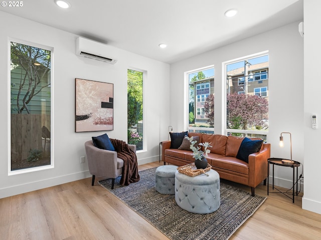living area featuring an AC wall unit, light wood-type flooring, baseboards, and recessed lighting