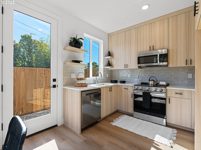 kitchen featuring stainless steel appliances, light brown cabinets, a sink, open shelves, and light countertops