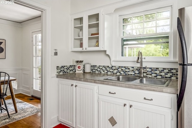 1968 SE 25th Ave, Portland, OR 97214 - kitchen featuring white cabinetry, glass insert cabinets, tasteful backsplash, wood finished floors, and a wainscoted wall