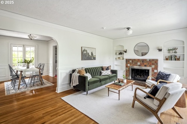 1968 SE 25th Ave, Portland, OR 97214 - living room with built in shelves, wood finished floors, crown molding, arched walkways, and a textured ceiling