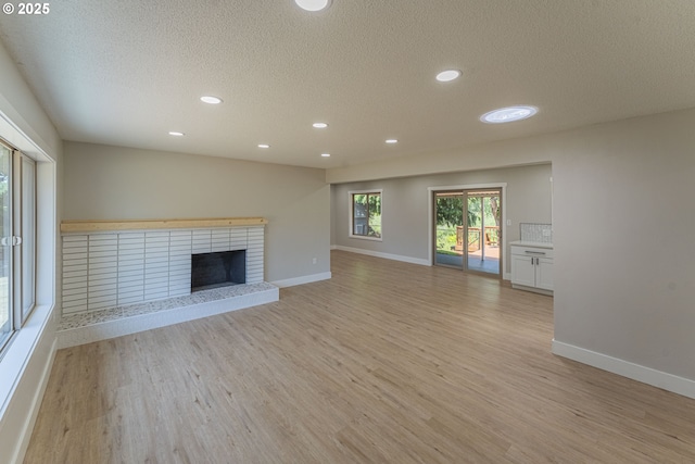 2859 NE 2nd Ave, Camas, WA 98607 - unfurnished living room with a textured ceiling, light wood-type flooring, recessed lighting, and a brick fireplace