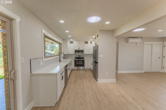 2859 NE 2nd Ave, Camas, WA 98607 - kitchen with stainless steel appliances, a wall mounted AC, tasteful backsplash, white cabinets, and light wood-style flooring