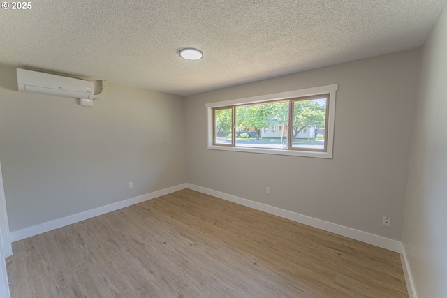 2859 NE 2nd Ave, Camas, WA 98607 - empty room with an AC wall unit, light wood-type flooring, and a textured ceiling