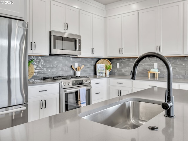 1155 SE Bugle Ave, Warrenton, OR 97146 - kitchen with stainless steel appliances, white cabinetry, backsplash, and light countertops