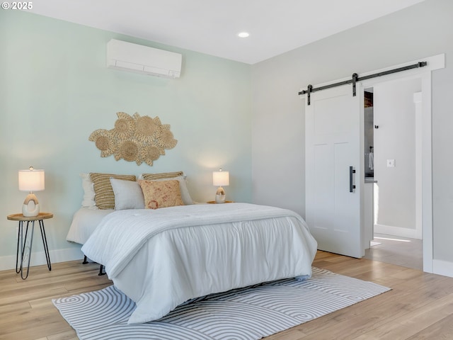 1155 SE Bugle Ave, Warrenton, OR 97146 - bedroom with a wall mounted air conditioner, a barn door, light wood-style flooring, and recessed lighting