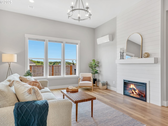 1155 SE Bugle Ave, Warrenton, OR 97146 - living area with a wall unit AC, wood finished floors, a large fireplace, and a chandelier