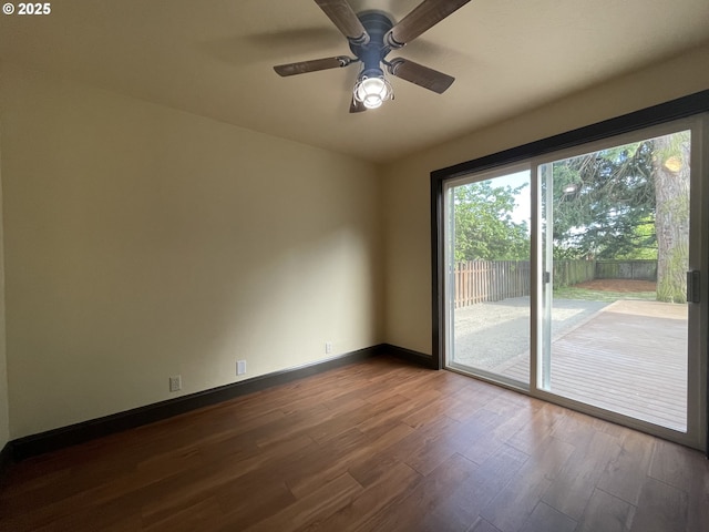 spare room with baseboards, a ceiling fan, and dark wood-style flooring