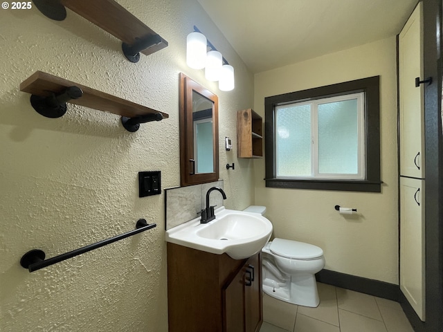 bathroom with tile patterned flooring, baseboards, toilet, and vanity
