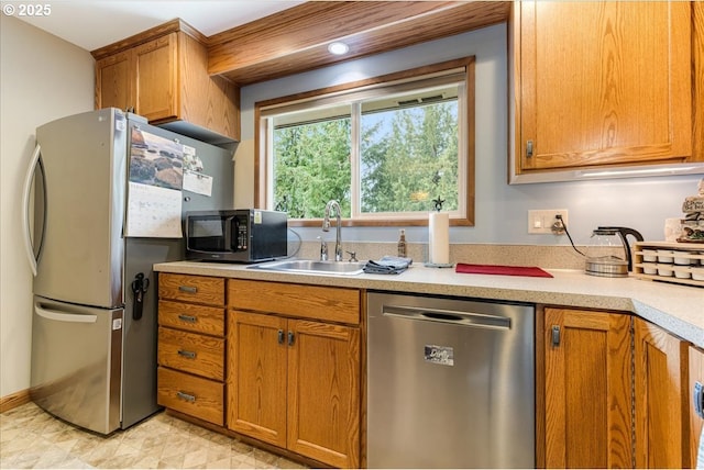 kitchen with brown cabinets, appliances with stainless steel finishes, light countertops, and a sink