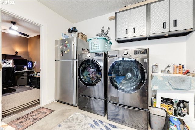 clothes washing area featuring washer and dryer, cabinet space, and a textured ceiling