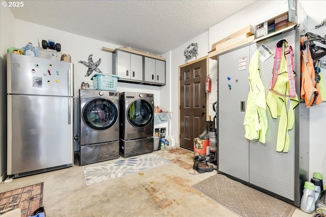 clothes washing area with a textured ceiling, cabinet space, and washer and clothes dryer