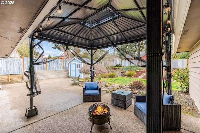 view of patio featuring an outbuilding, a fire pit, a storage shed, and a fenced backyard