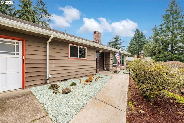 doorway to property featuring a garage and a chimney