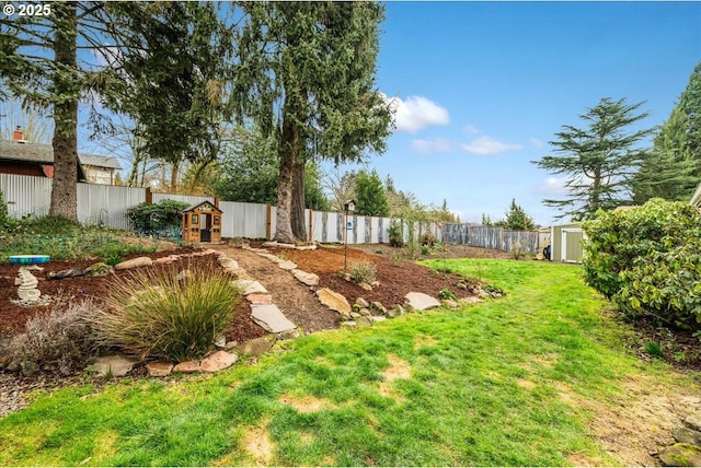 view of yard with a storage unit, an outbuilding, and a fenced backyard