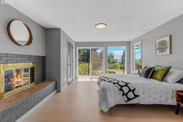 8318 SE Middle Way, Vancouver, WA 98664 - bedroom featuring access to outside, a fireplace, a textured ceiling, and light wood-style flooring
