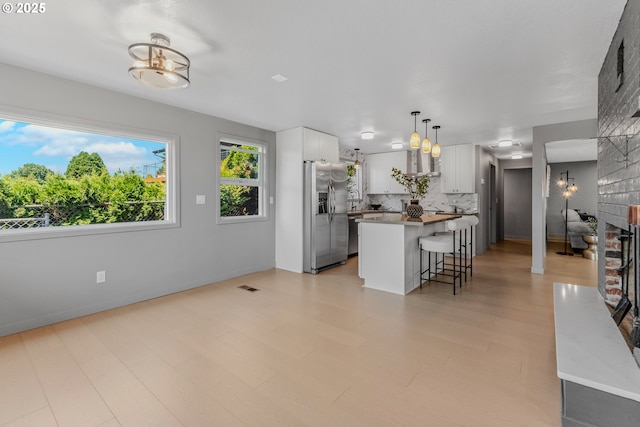 8318 SE Middle Way, Vancouver, WA 98664 - kitchen with stainless steel refrigerator with ice dispenser, a breakfast bar, tasteful backsplash, white cabinets, and a center island