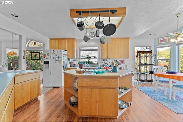 kitchen with light wood finished floors, white fridge with ice dispenser, and open shelves
