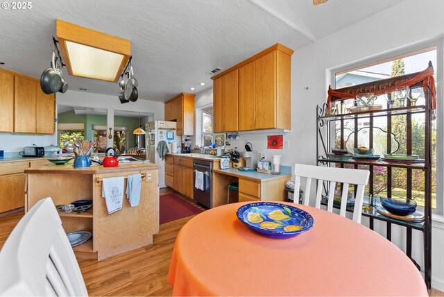 kitchen with light wood-type flooring, a center island, freestanding refrigerator, open shelves, and dishwashing machine